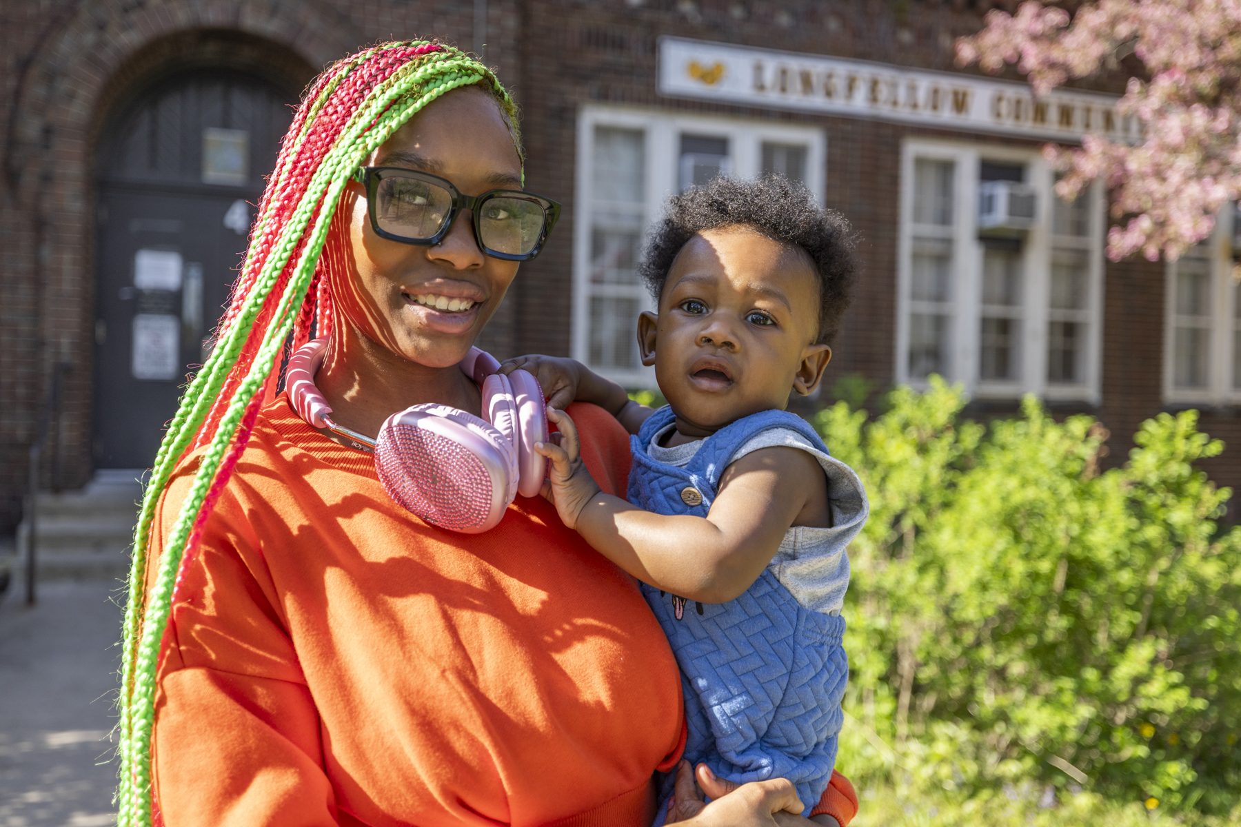 Raniya, 19, a Longfellow student, smiling as she holds her baby son outside the school